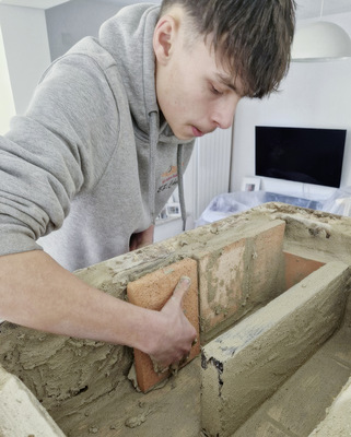 Efe beim Vorschub der Kacheln und der Auskleidung der Züge mit maßgeschneiderter Schamotte. - © Foto:  Keller´s Kaminhof
